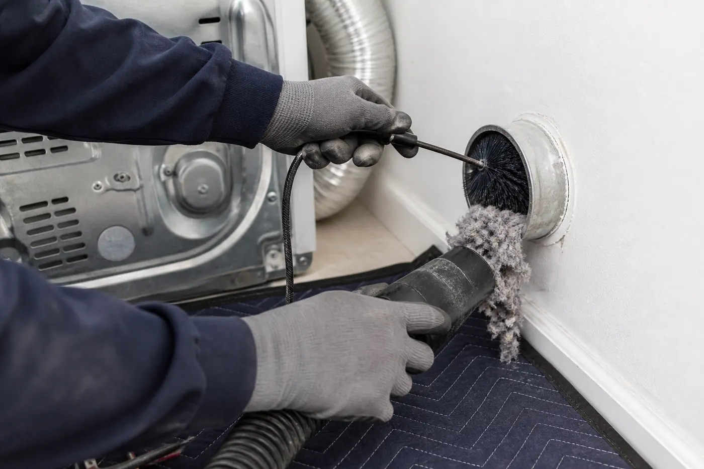 Close-up detail of a rotary cleaning brush removing lint from a dryer vent duct in Greater Boston